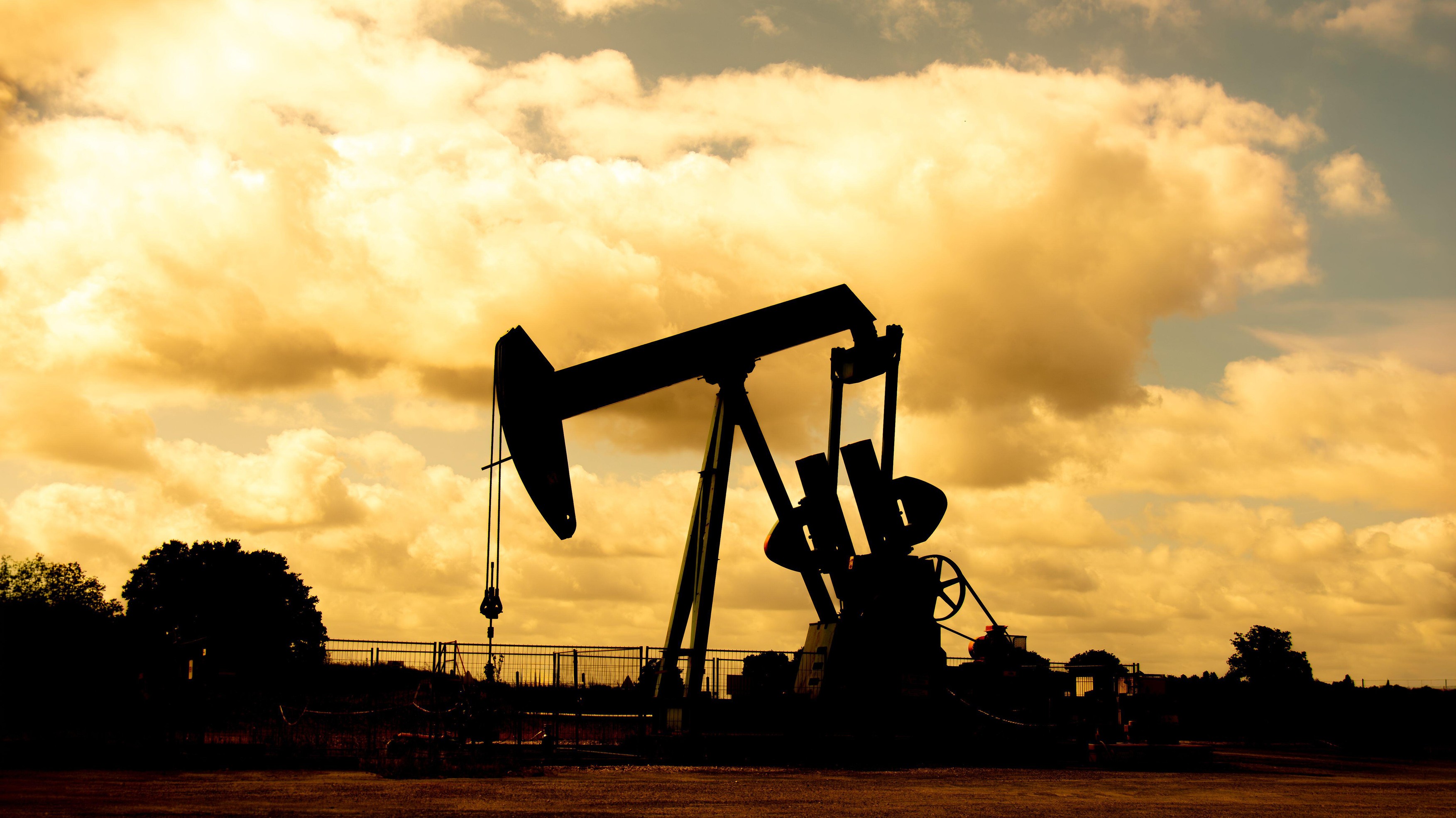 Crude oil extraction from an oil field. Pumpjack silhouetted against a background of clouds at sunset. Concepts of petroleum industry and oil prices